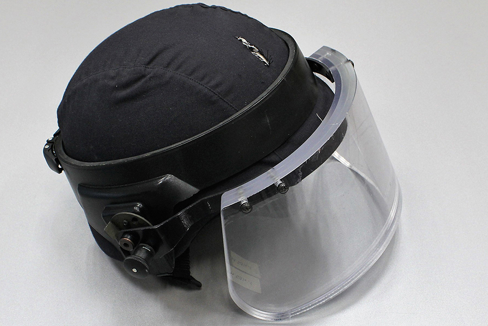 Helmet with a cut in the protective fabric and an impact mark on the protective visor.