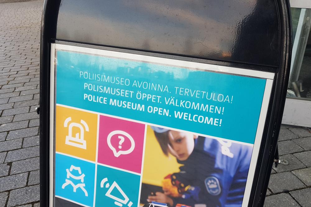 Skylt framför ytterdörren med texten ”Polismuseet öppet. Välkommen!”.