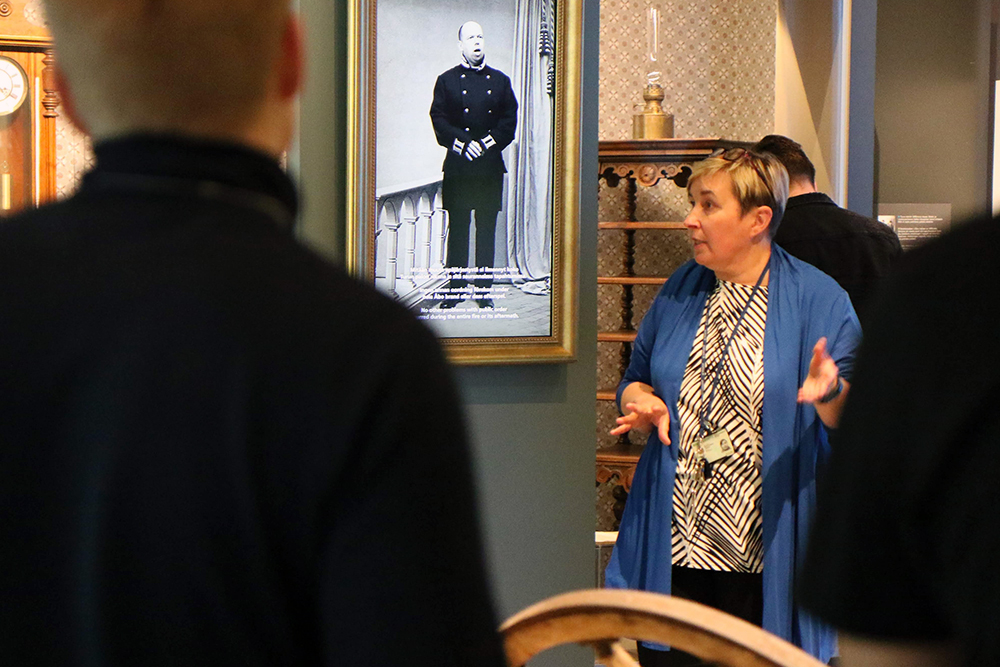 Museiguiden berättar för en grupp besökare om polisens historia i en utställning på Polismuseet.
