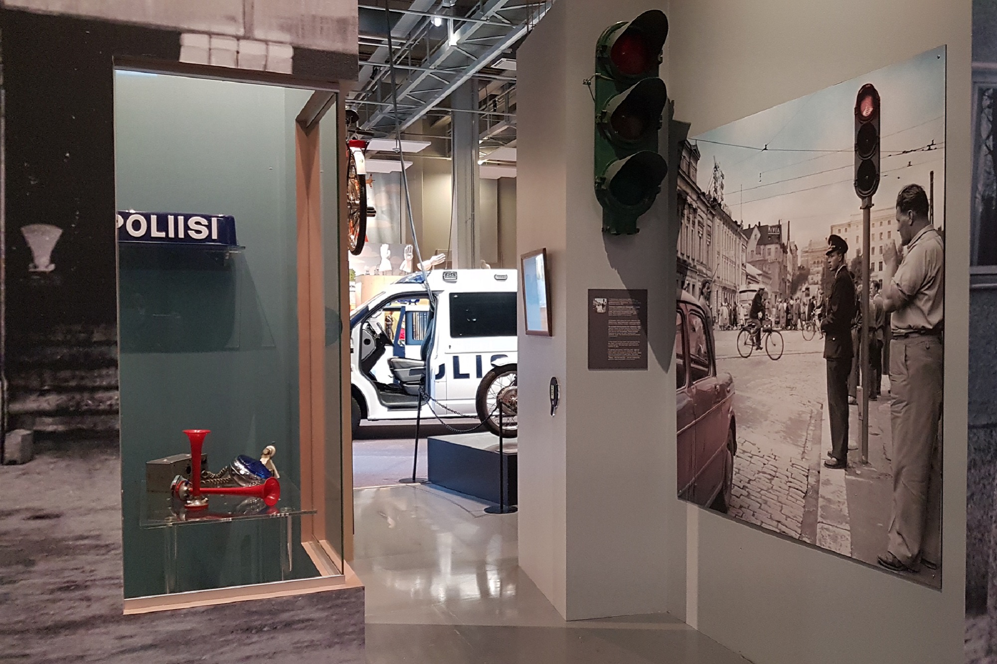 Bild av museets utställning. Bilden visar en vitrin, ett fotografi av stadstrafik och en polisbil. Bild Polismuseet, Pia Penttilä