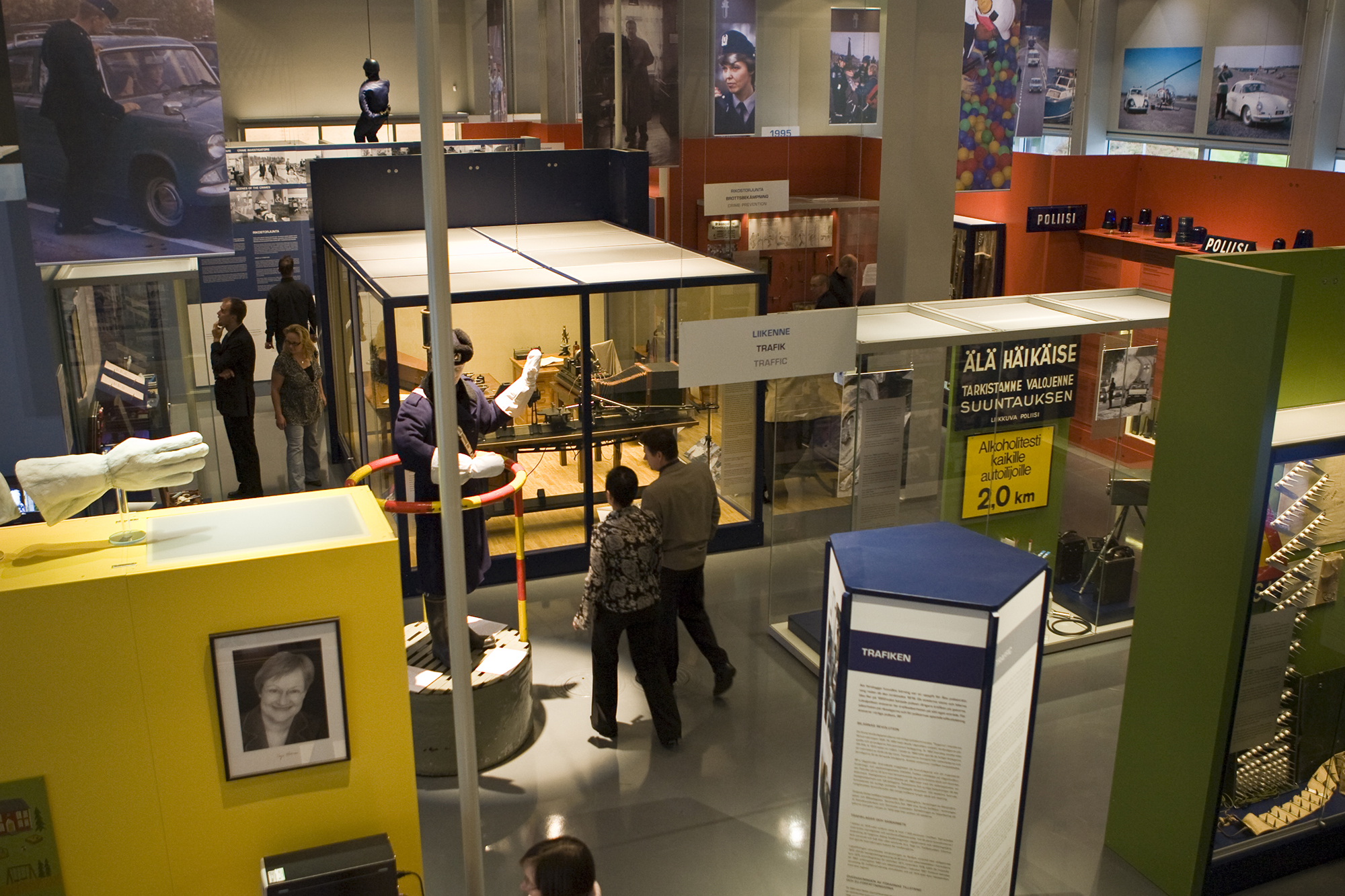 Allmän bild av Polismuseets utställning. På bilden går museibesökare runt mellan vitrinerna, i lokalen syns bland annat fotografier och föremål med anknytning till polisens arbete. Bild Polismuseet