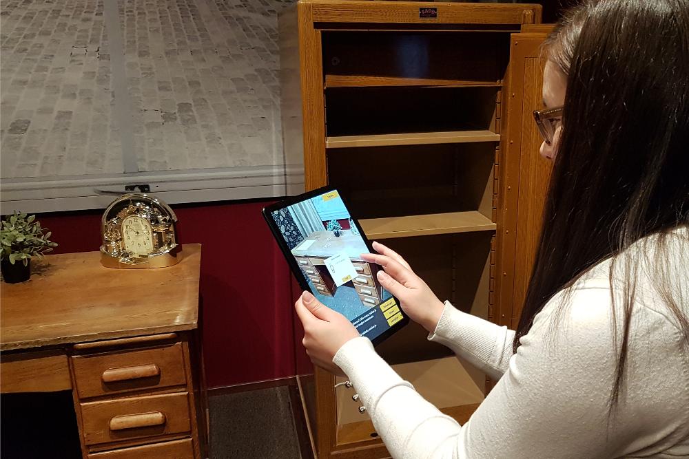 A museum visitor using a tablet to search for clues in the crime scene game.