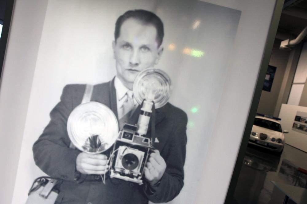 A black-and-white photograph of a man holding an old camera in his hands.